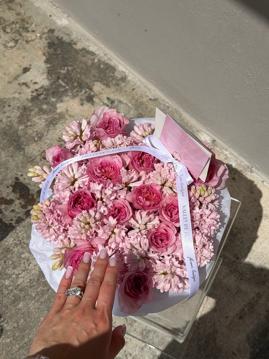Pink garden roses and hyacinth arranged in a round box for a colorful birthday celebration