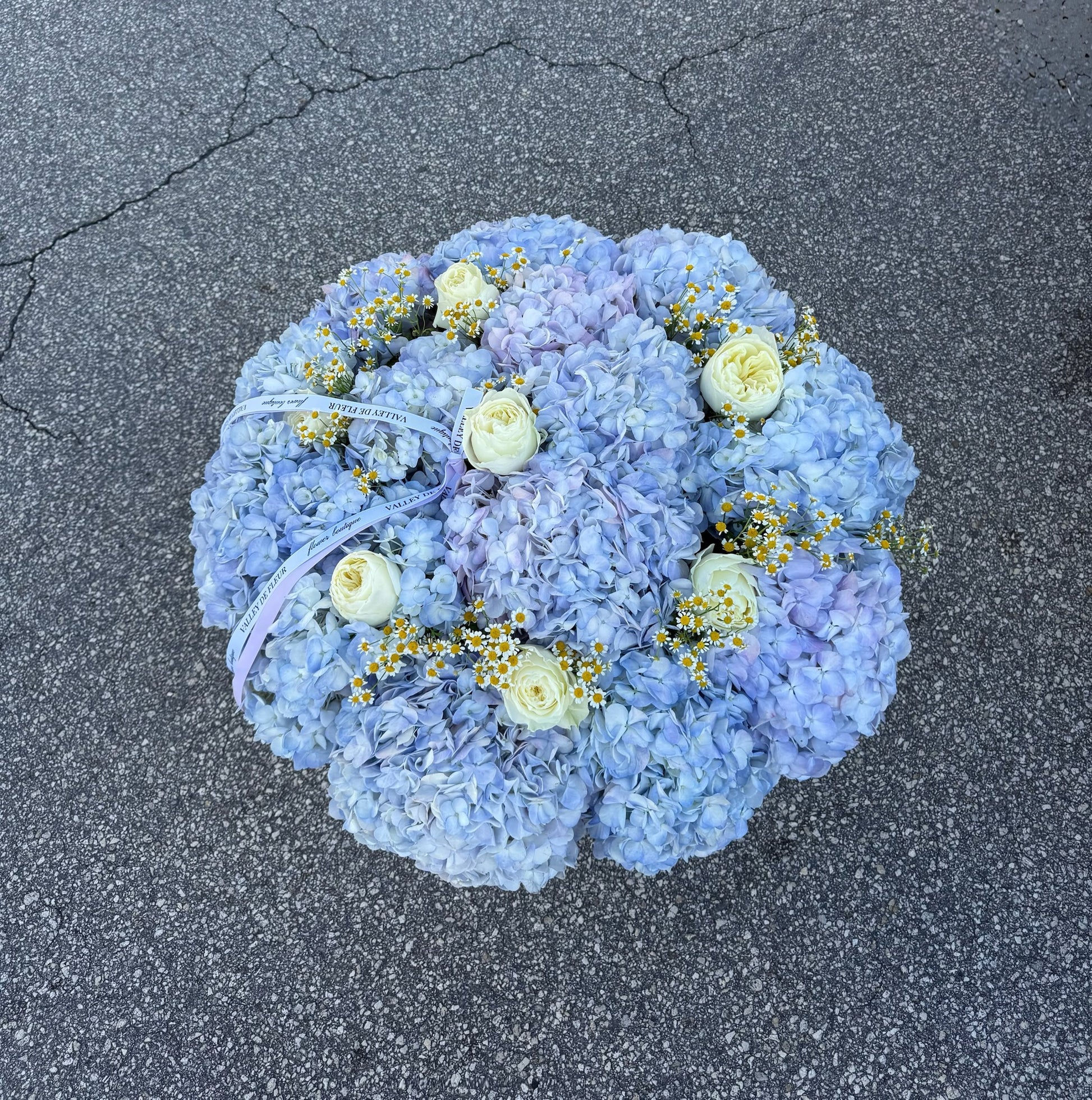 Large Blue Cloud hydrangea flower basket with fresh blue hydrangeas, white roses, and chamomile flowers by Valley De Fleur