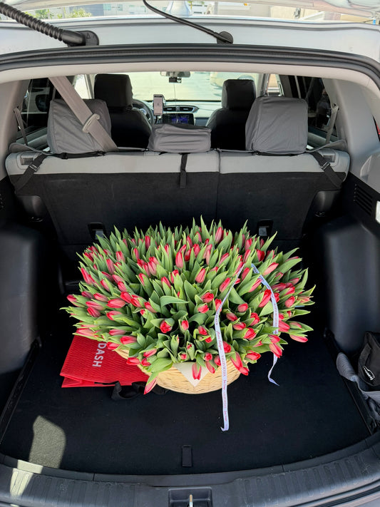 Red tulip birthday flower arrangement in a delivery vehicle, ready for delivery