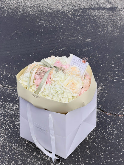 Soft hydrangeas and mixed roses wrapped as a blush birthday bouquet
