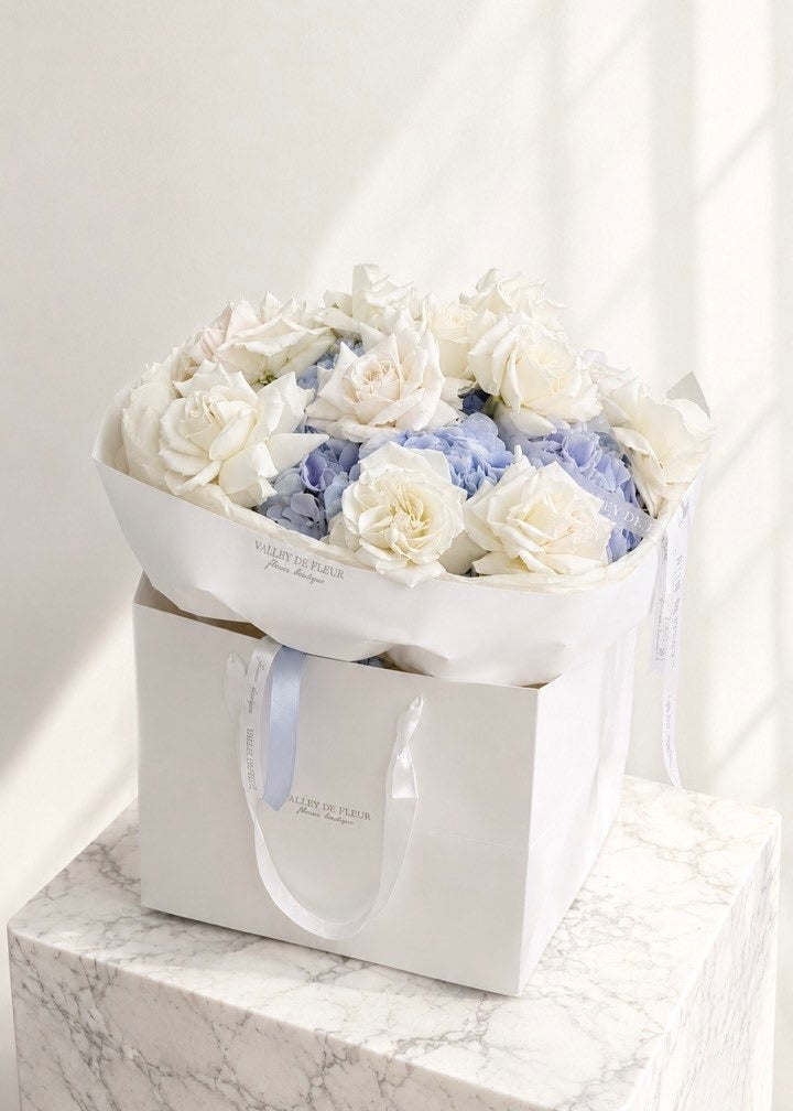 Lavender hydrangeas surrounded by white French roses in a birthday flower bouquet