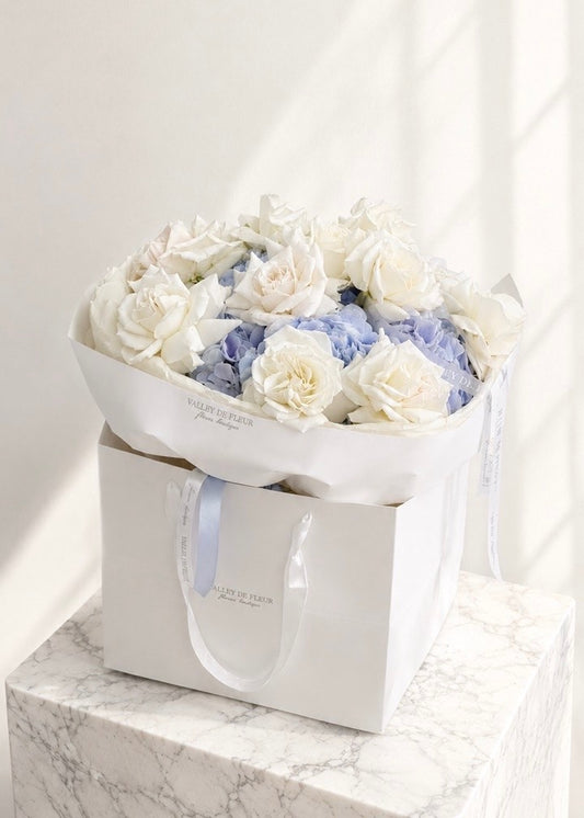 Lavender hydrangeas surrounded by white French roses in a birthday flower bouquet