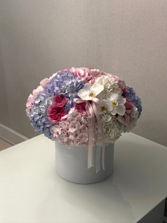 Pastel hydrangeas, garden roses and white orchids in a medium birthday flower arrangement
