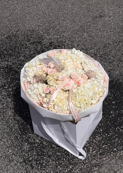 White hydrangeas and light pink Majolica roses arranged as birthday flowers in a wrapped bouquet