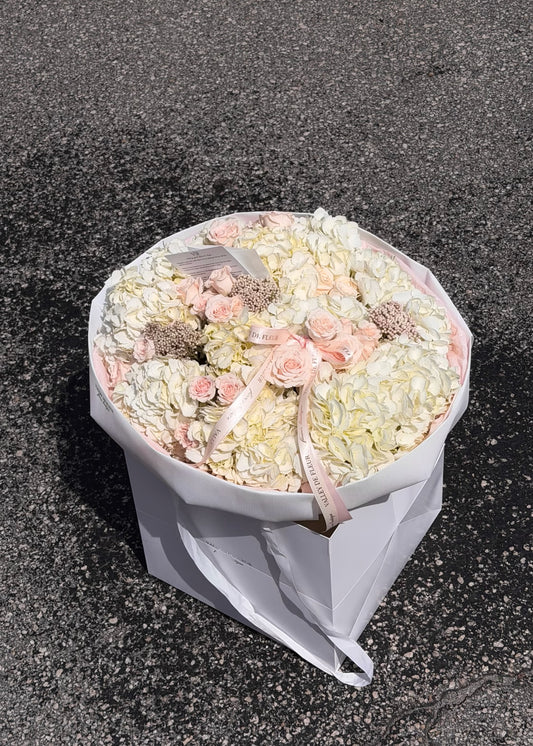 White hydrangeas and light pink Majolica roses arranged as birthday flowers in a wrapped bouquet